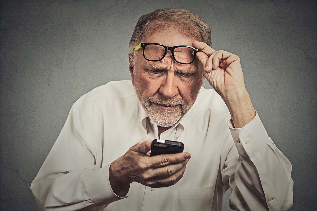 Man squinting to see text on a cell phone