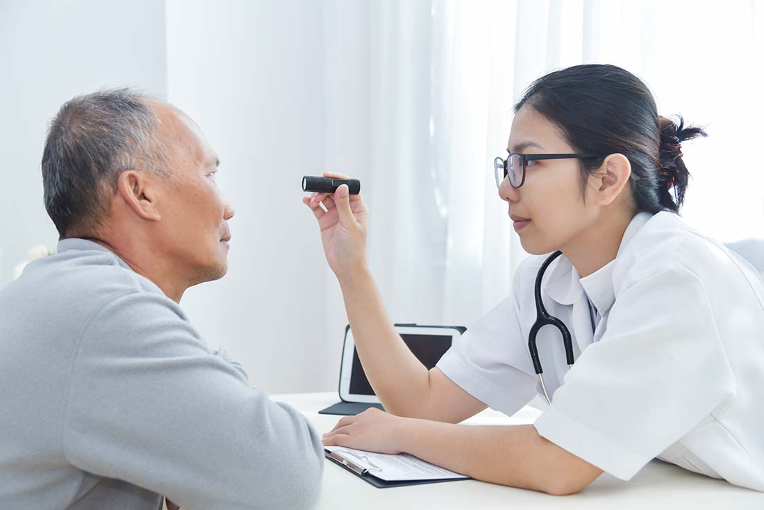 Doctor checking patients eyes with light